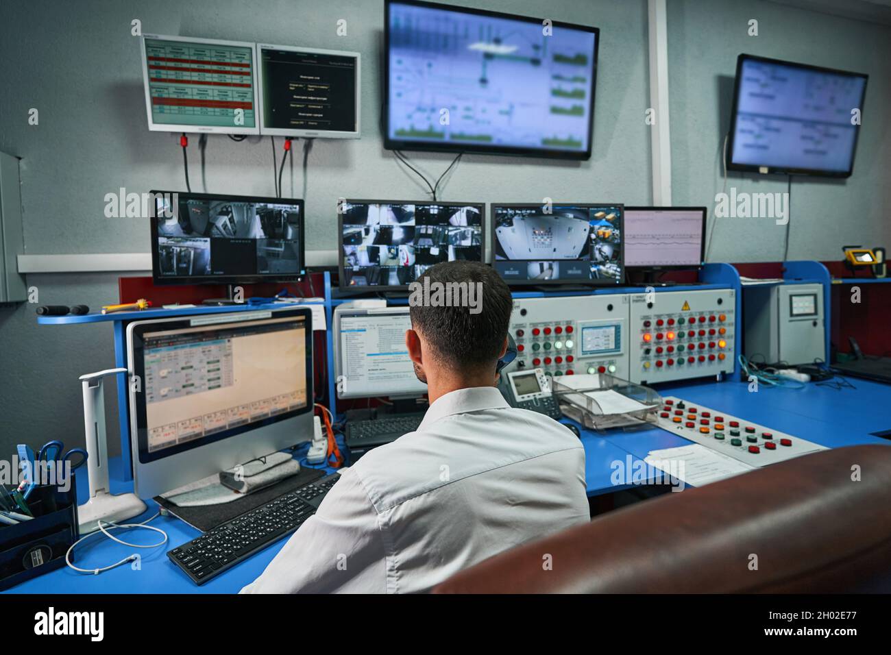 Server administrator looking after data center rooms through monitors Stock Photo