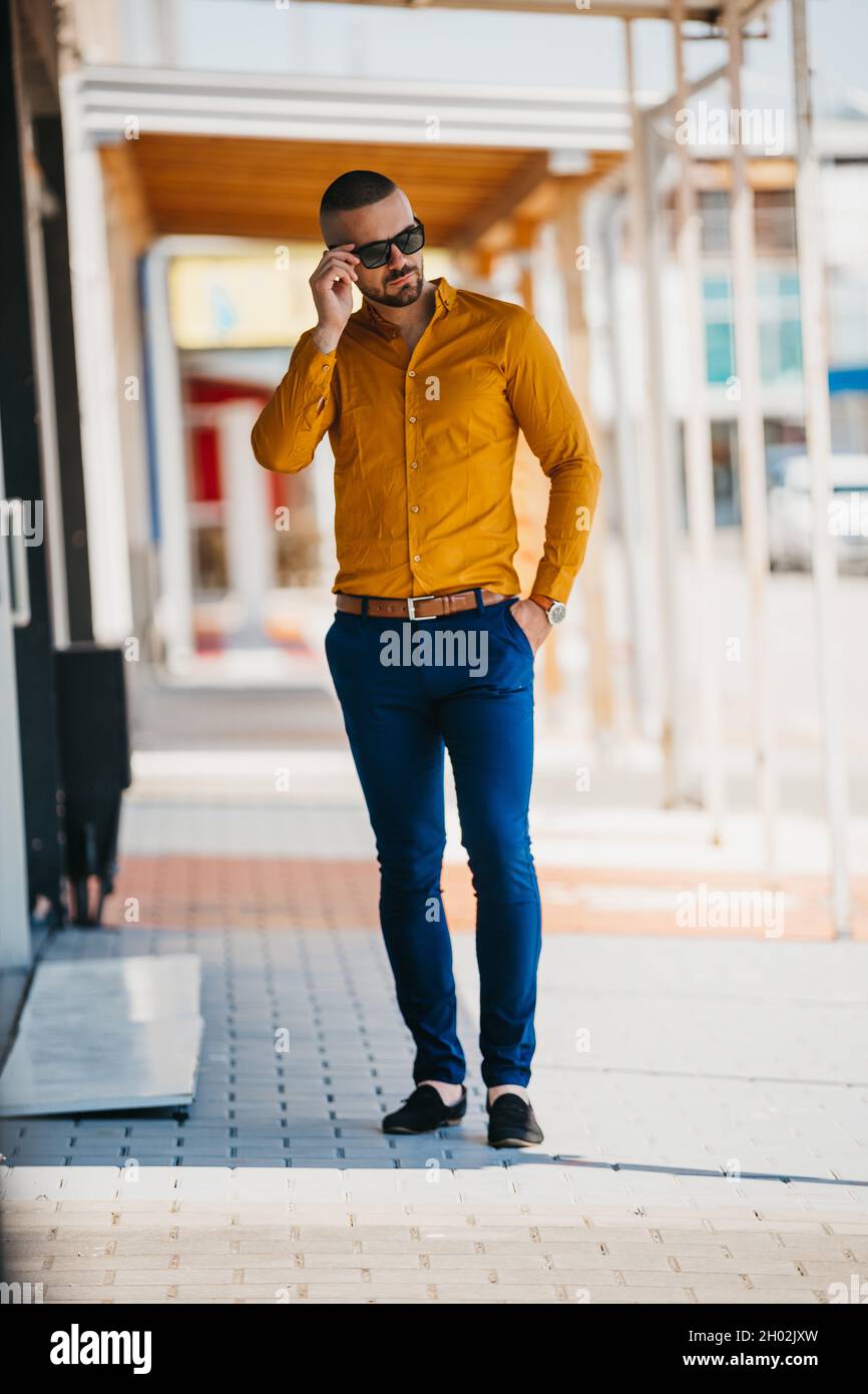 Cool handsome Caucasian man wearing an elegant mustard shirt and sunglasses  posing outdoor Stock Photo - Alamy