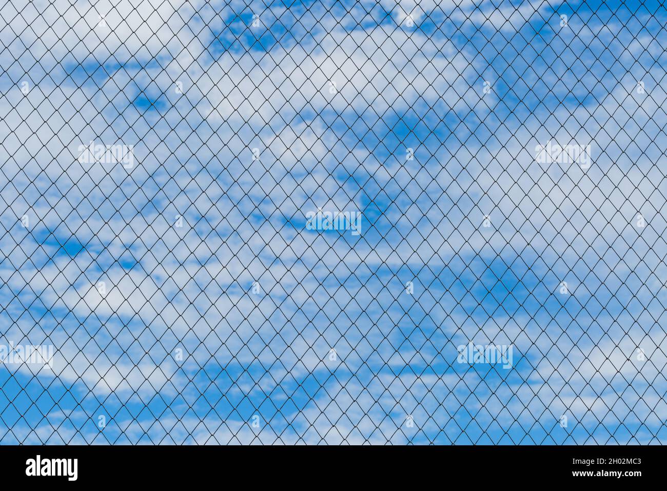 Metal wire fence with blue sky and clouds background Stock Photo - Alamy