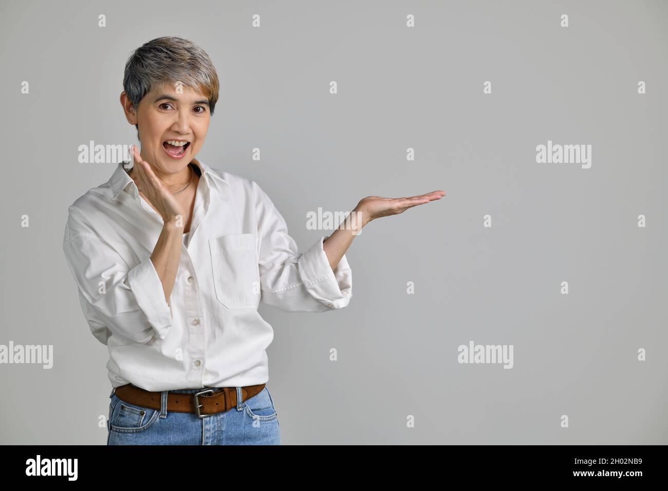 Middle aged Asian woman showing empty copy space on the open hands palm ...