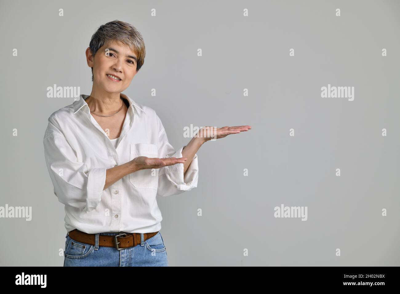 Middle aged Asian woman showing empty copy space on the open hands palm ...