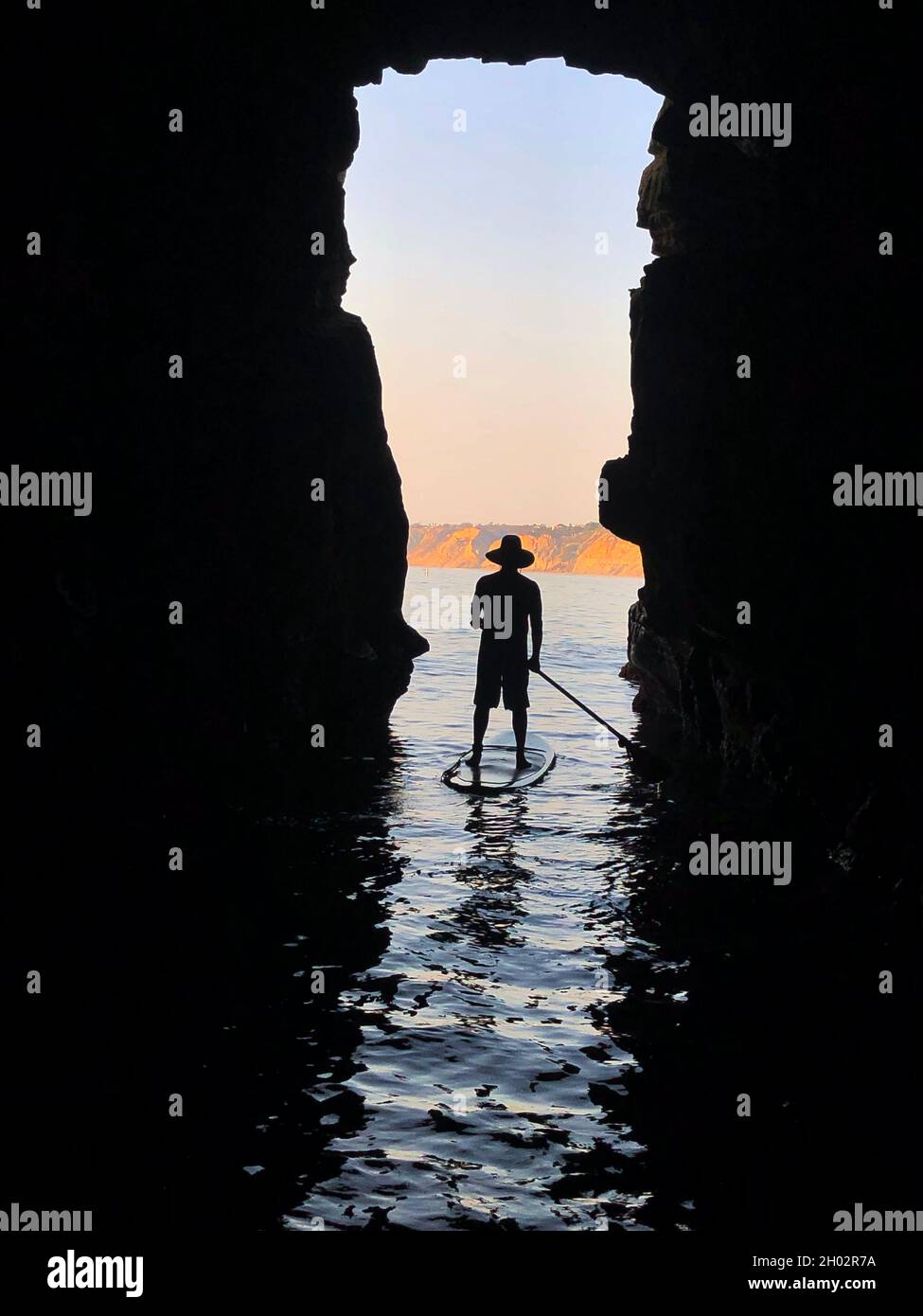 San Diego, California, USA. 12th Aug, 2021. A paddleboarder rides out of a cave at sunset on a clear, calm summer day in La Jolla Cove in San Diego. (Credit Image: © K.C. Alfred/ZUMA Press Wire) Stock Photo