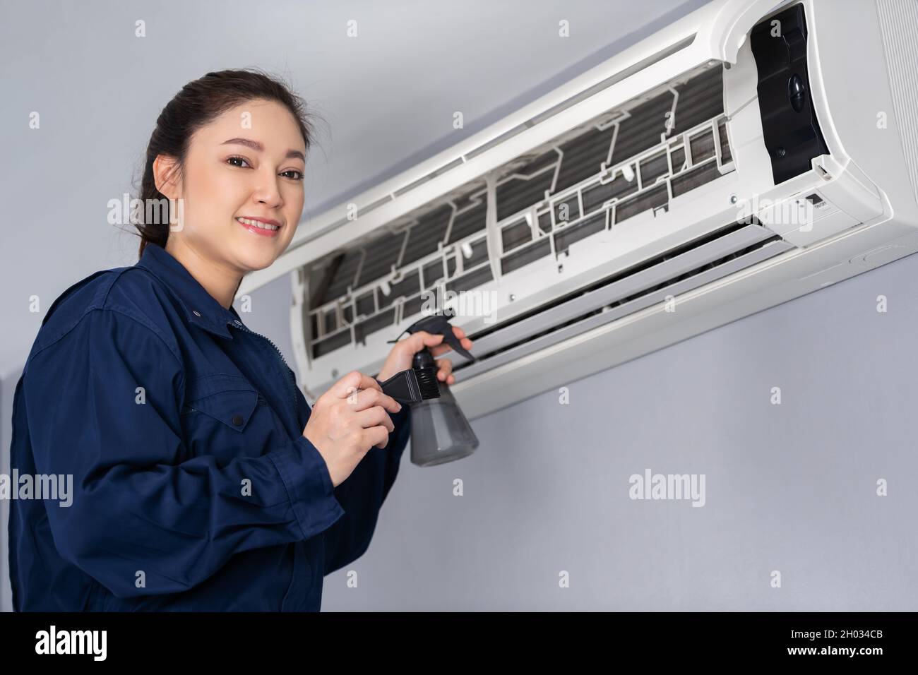 female technician service cleaning the air conditioner indoors Stock Photo