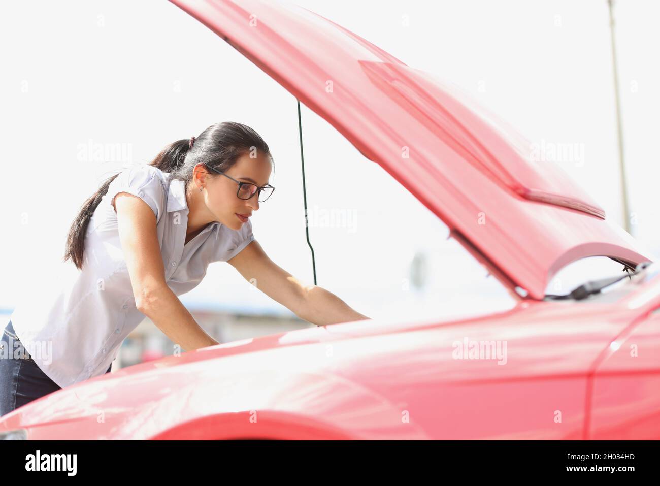 Focused woman looks at car engine closeup Stock Photo