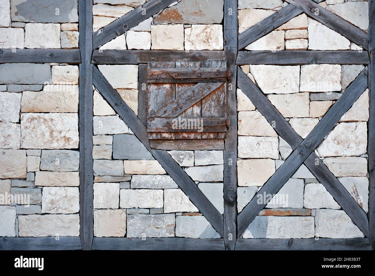 Ancient window exterior with closed wooden blinds on stone walls