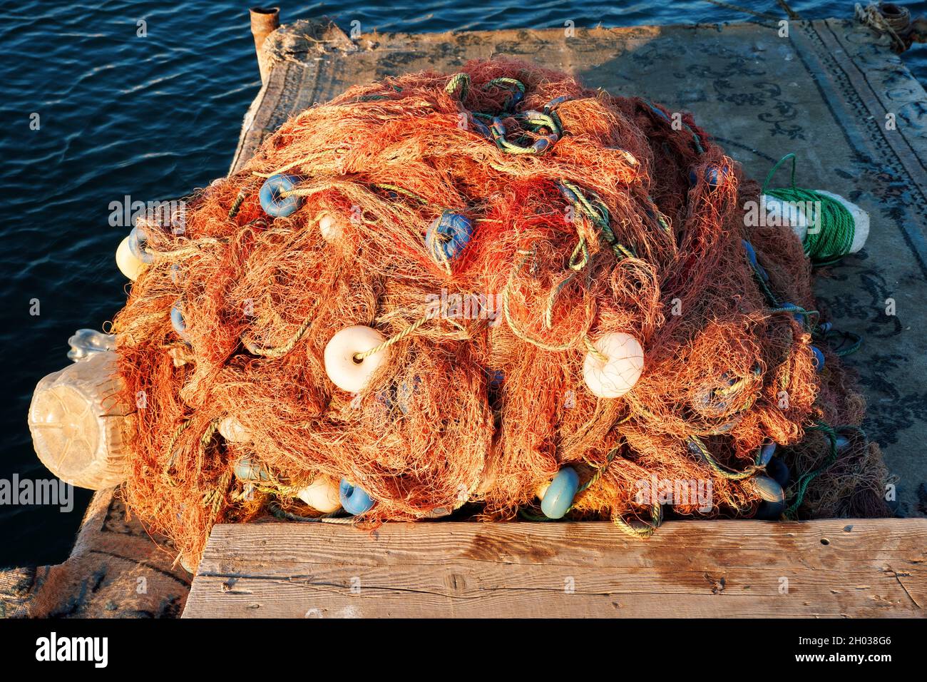 Pile of industrial fishing net with buoy on the wooden dock Stock Photo -  Alamy