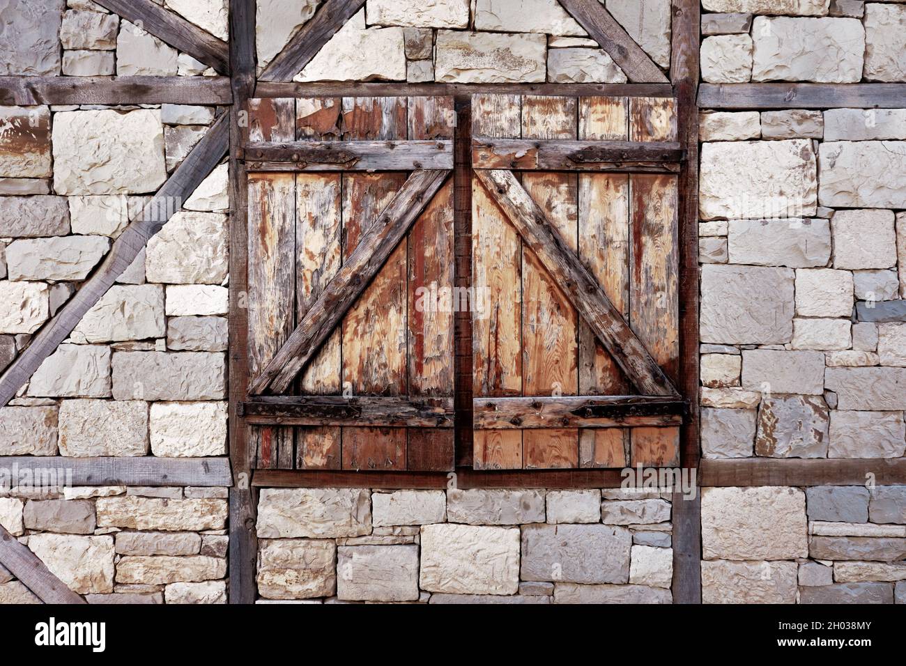 Ancient window exterior with closed wooden blinds on stone walls