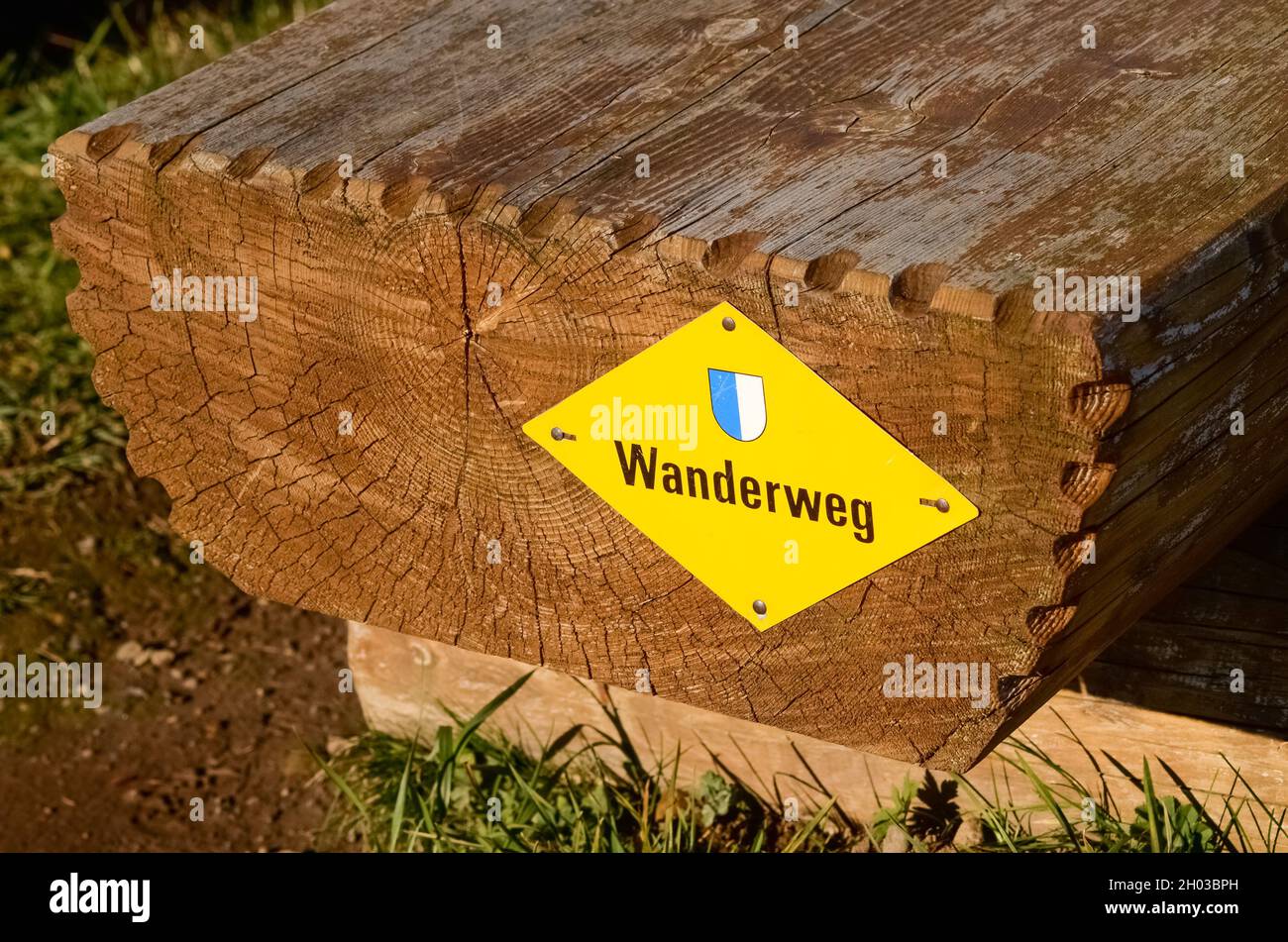 Wooden bench and yellow sign Wanderweg (Hiking path) in the swiss alps, Switzerland, Europe Stock Photo