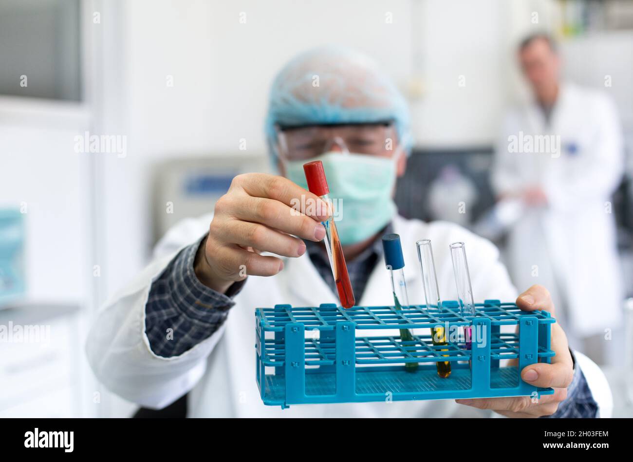 Close up of researcher's hand holding test tubes with colorful liquids ...