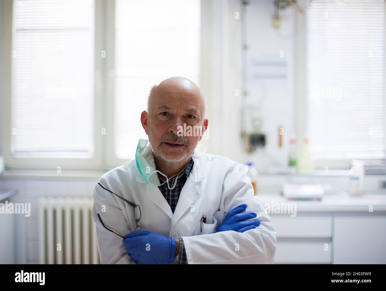 Portrait of senior biologist in protective workwear standing with crossed arms in laboratory Stock Photo