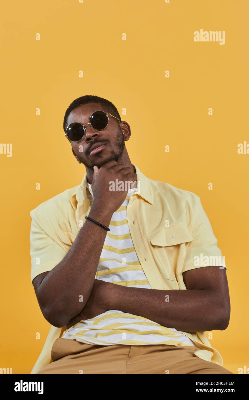 Man in sunglasses and yellow shirt smiling at camera hi res stock