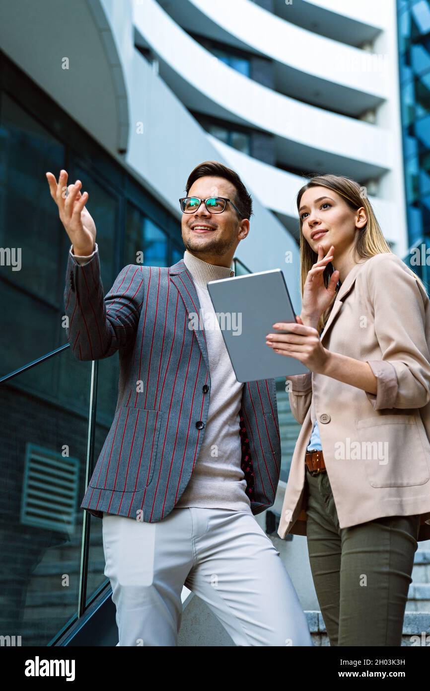 Successful young business people talking, working together in front of modern business building Stock Photo