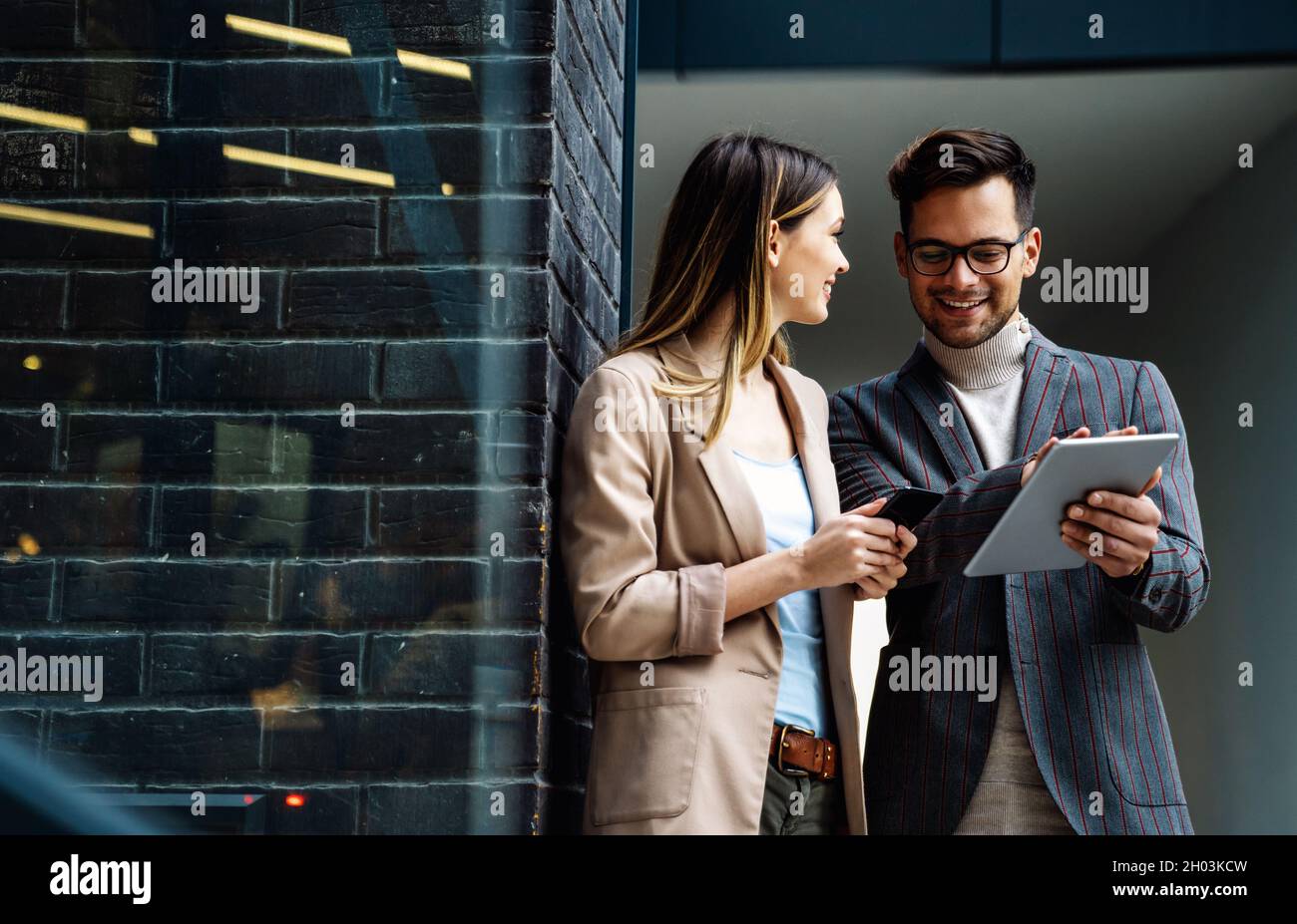 Successful young business people talking, working together in front of modern business building Stock Photo