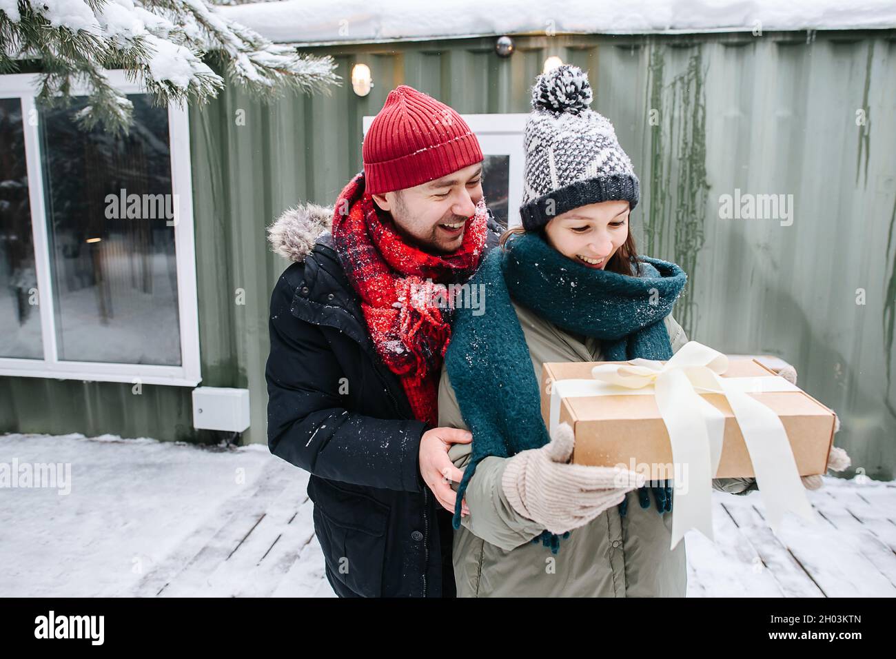 Smiling man in winter clothes gifted woman with a present in a bow-tied box Stock Photo