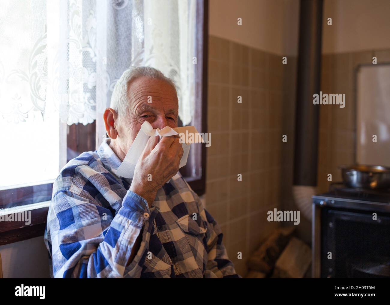 Old man holding tissue and blowing nose. Virus and grippe concept Stock Photo