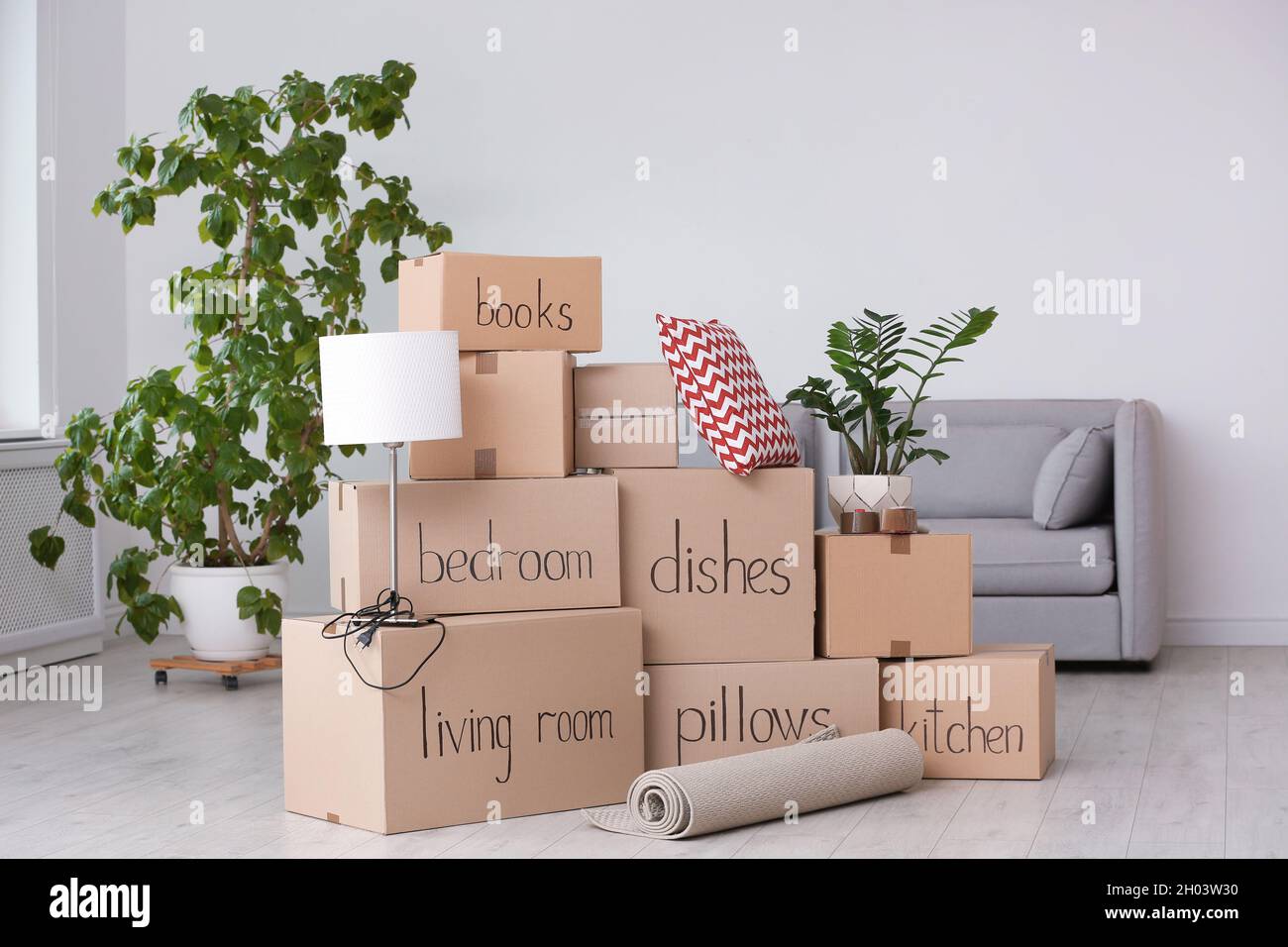 Pile of moving boxes and household stuff in living room Stock Photo - Alamy