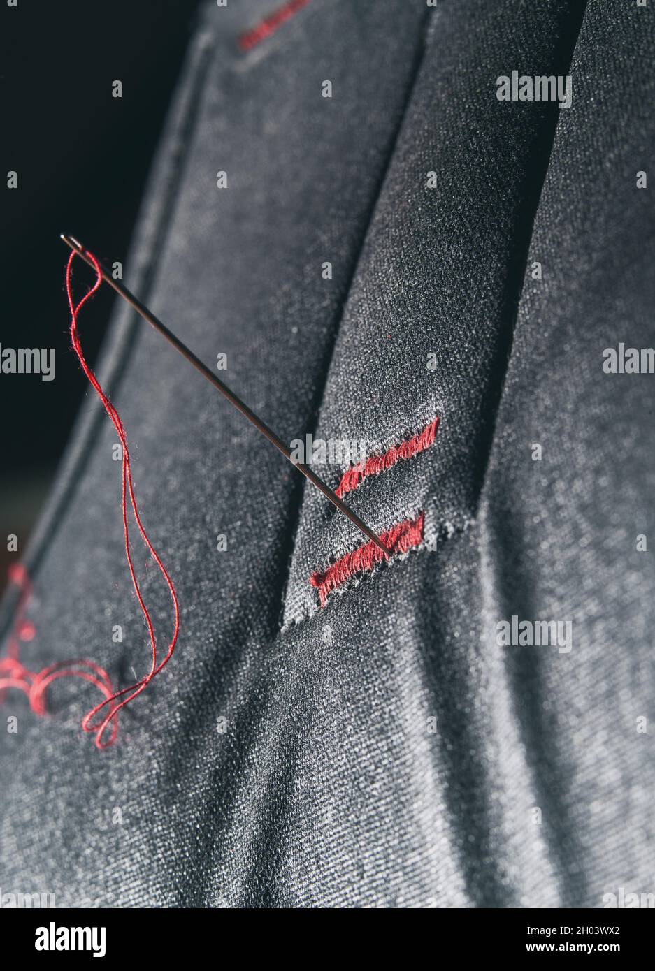 Close up of needle with red thread on gray fiber Stock Photo - Alamy