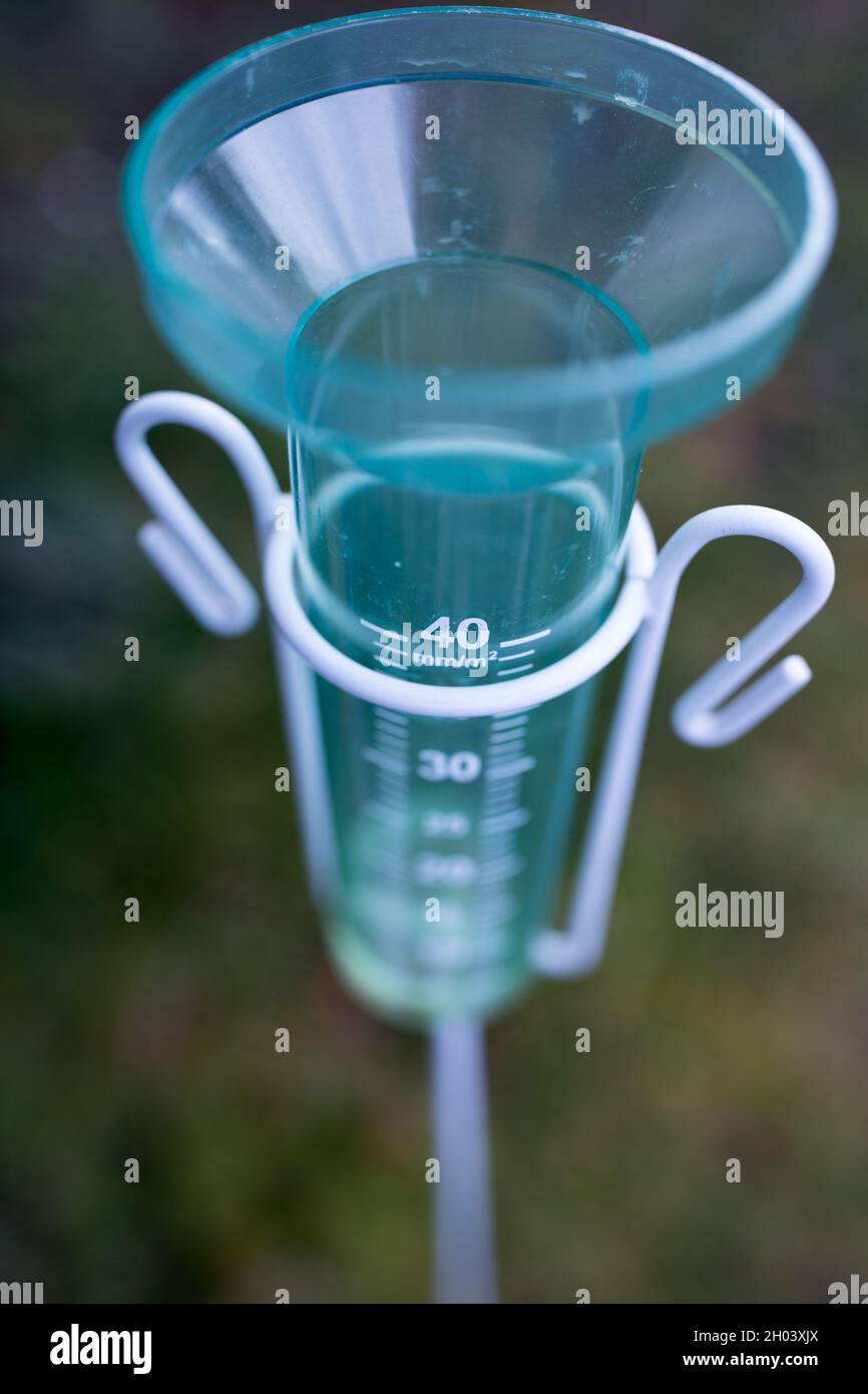 Close up of plastic rain gauge in field. Measuring equipment for