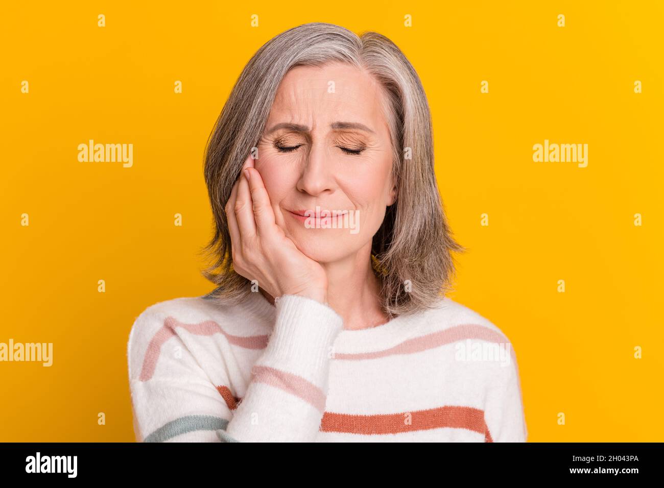 Photo of sad white hairdo aged lady hand cheek wear sweater isolated on yellow color background Stock Photo