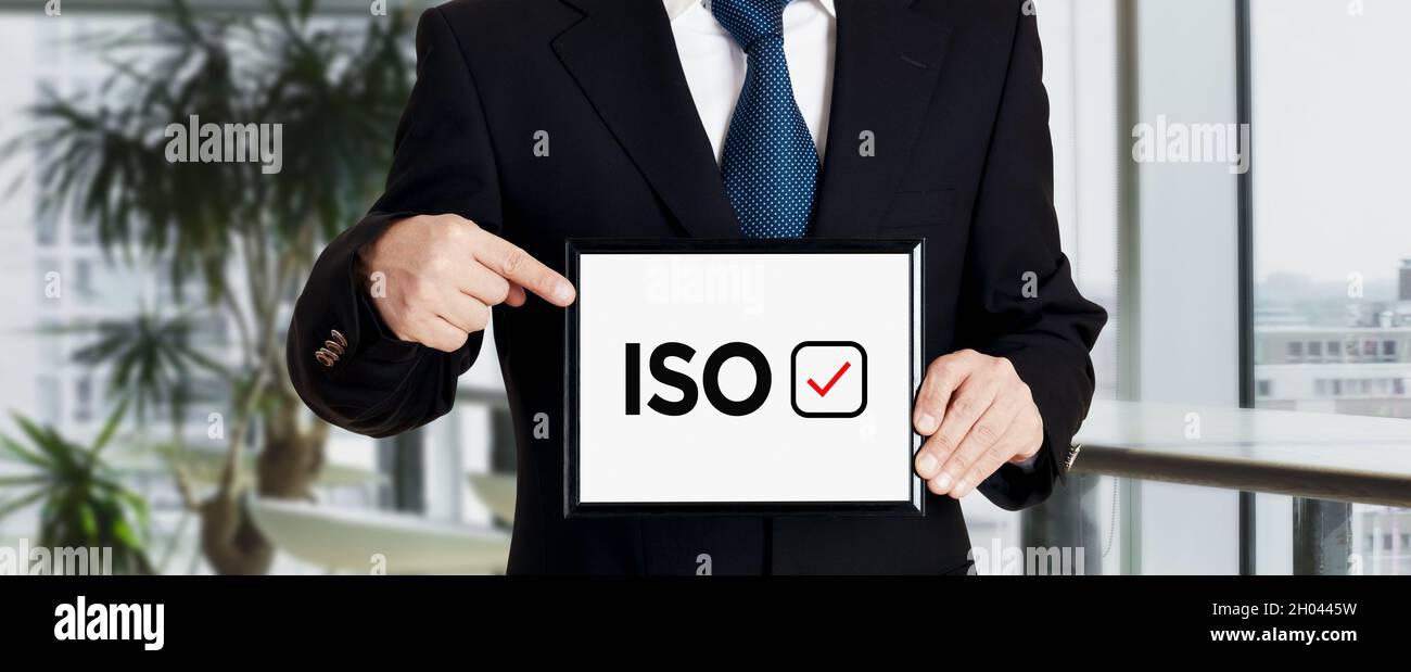 Businessman holds a signboard and points his finger to the word ISO ...