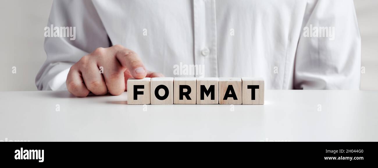 Businessman pressing his finger on the wooden cubes with the word format. Formatting or resetting concept. Stock Photo