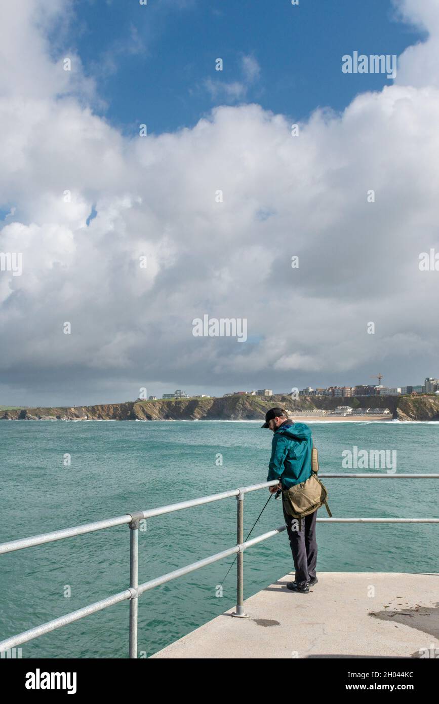 An angler fishing from the North Quay in Newquay Harbour in Cornwall. Stock Photo