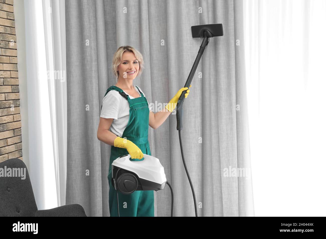 Female janitor removing dust from curtain with steam cleaner indoors Stock  Photo - Alamy