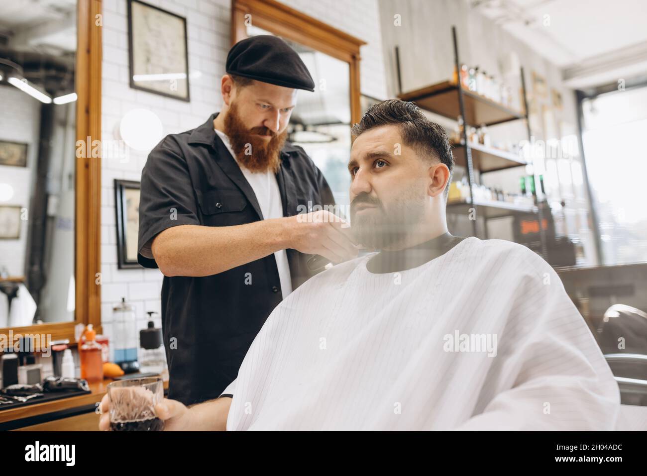 Two handsome men at barbershop. Stylish red-bearded barber and client ...