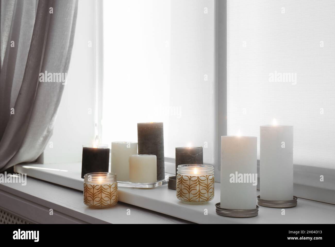 Burning candles on window sill in room Stock Photo Alamy