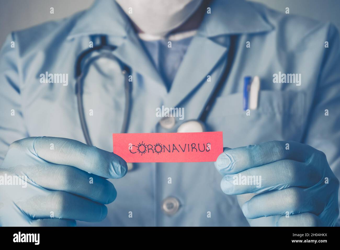 Concept of Covid-19 pandemic. Doctor holding a red paper that written coronavirus. Stock Photo