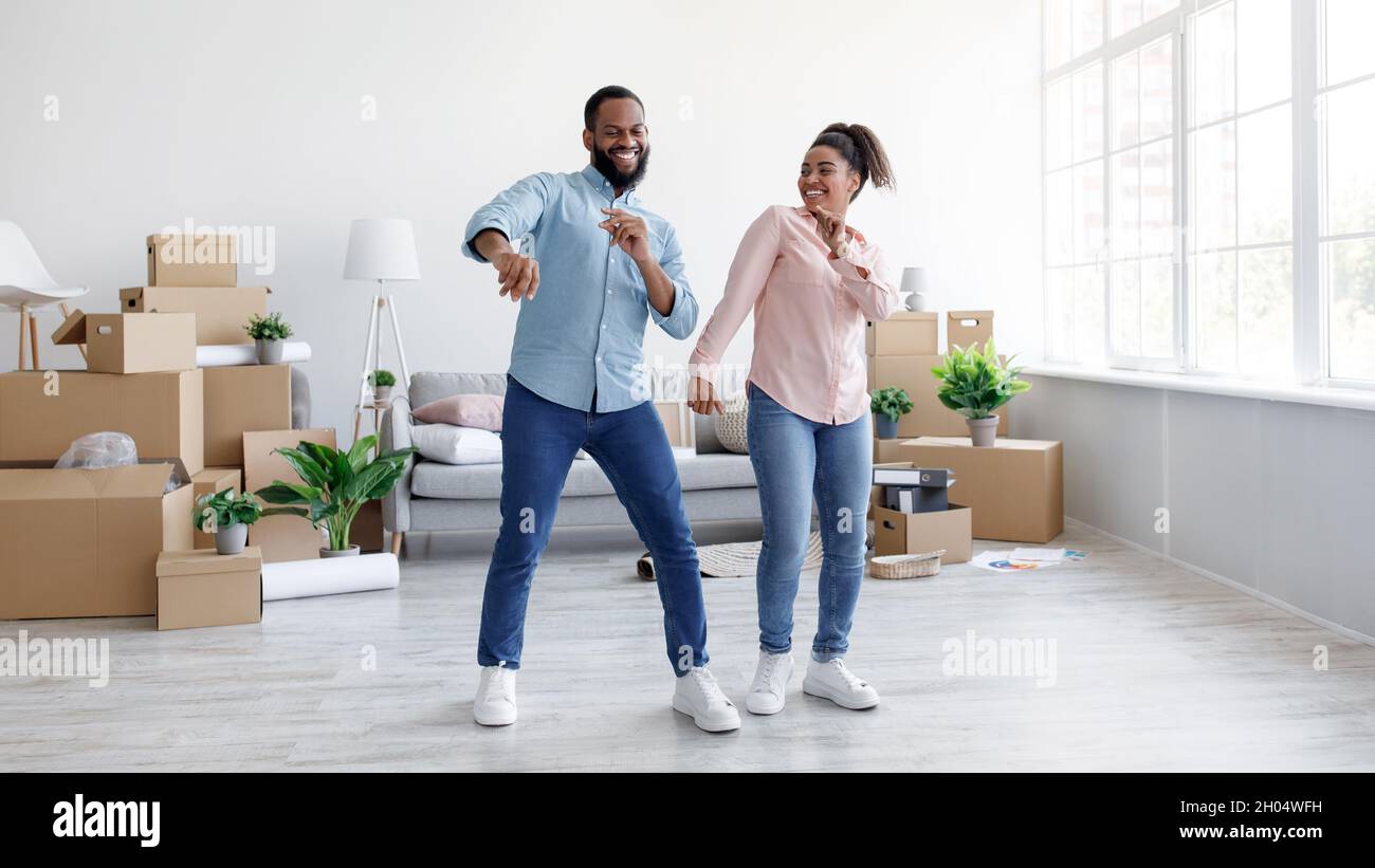 Satisfied young african american husband and wife dancing in new ...