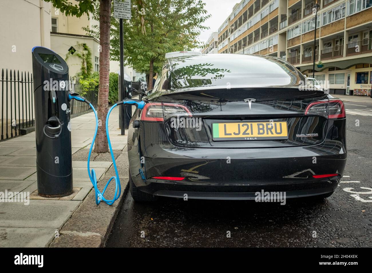 London- October 2021: Tesla electric car on charge at on-street charging station in south west London Stock Photo