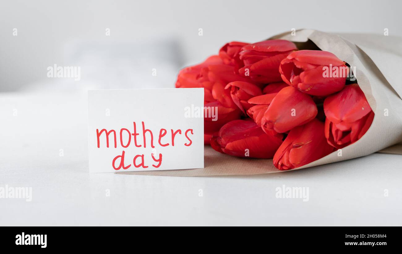Mothers Day. A bouquet of red tulips and a card with the inscription