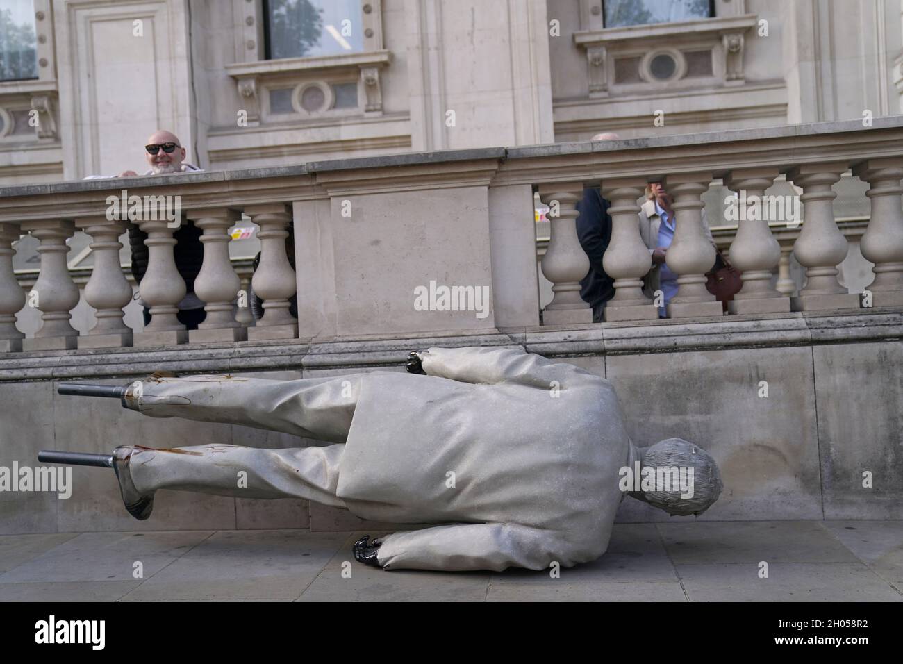 A statue of Prime Minister Boris Johnson splattered with oil on the ground after campaigners from Greenpeace demonstrated outside Downing Street, London, against the Cambo oil field off the west coast of Shetland. Picture date: Monday October 11, 2021. Stock Photo