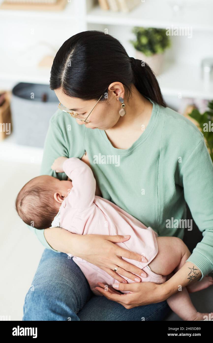 Young mother holding her baby on hands and feeding her before sleeping Stock Photo