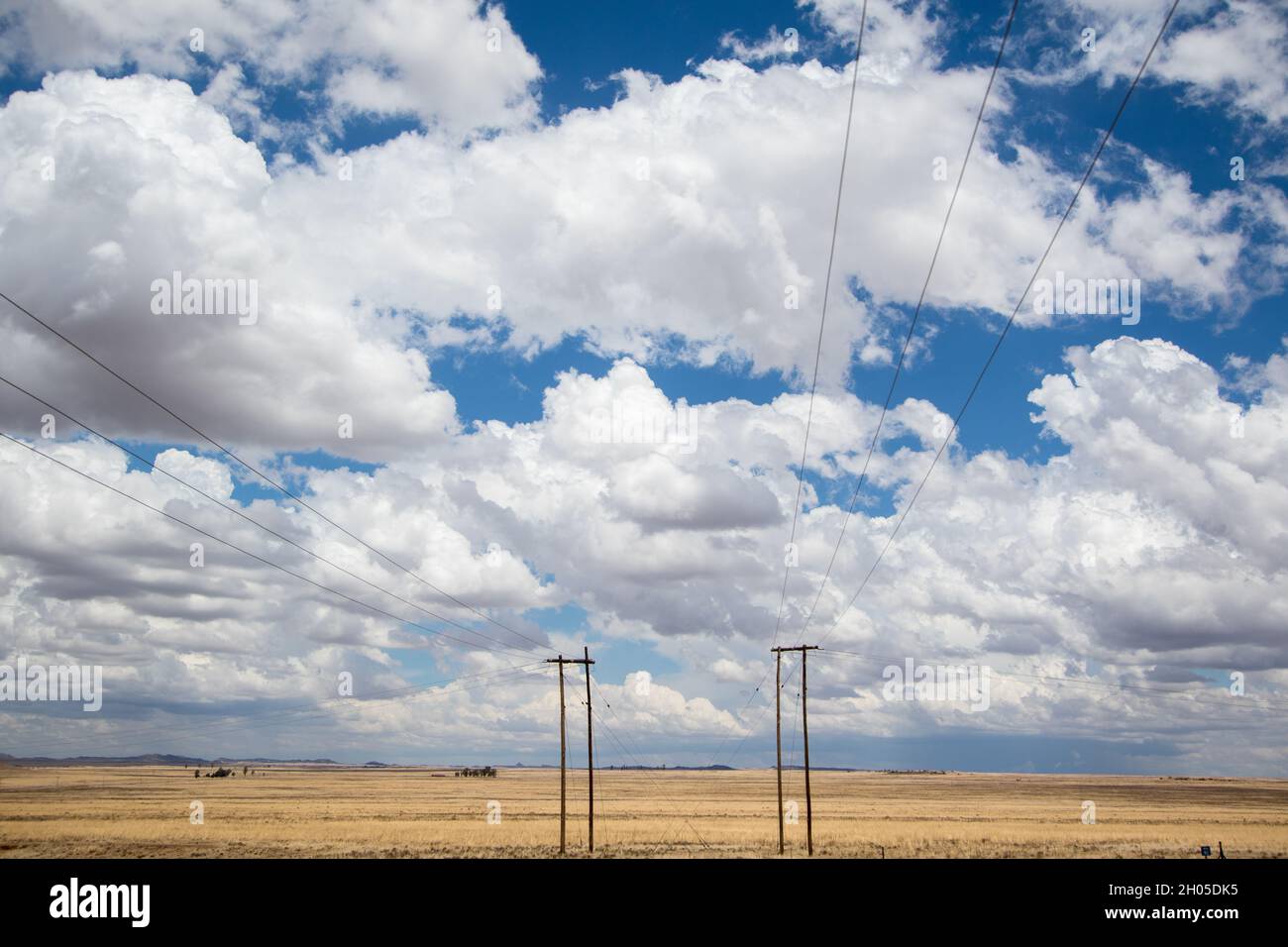 A cloudy sky over a flat, open landscape with a road leading into the distance. Stock Photo