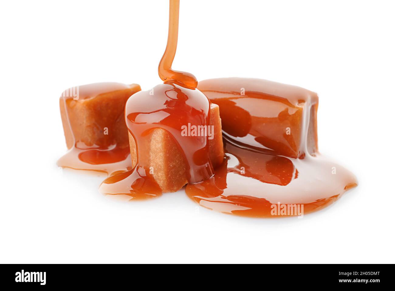 Pouring caramel sauce onto delicious candies on white background Stock ...