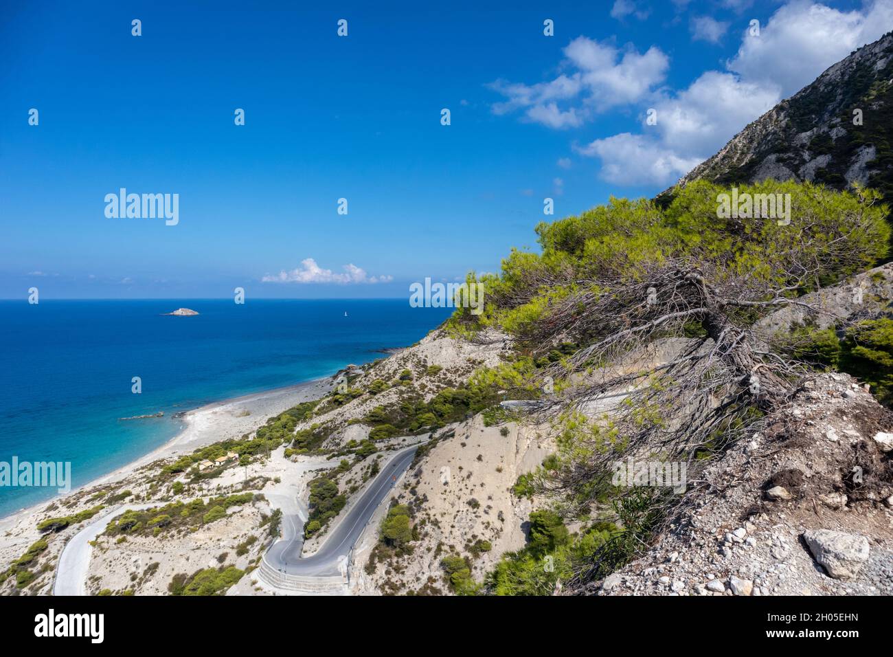 Driving mountain serpentine steep road to Gialos pebble beach with turquoise water and clear blue sky, Lefkada island, Ionian sea, Greece. Sunny summe Stock Photo