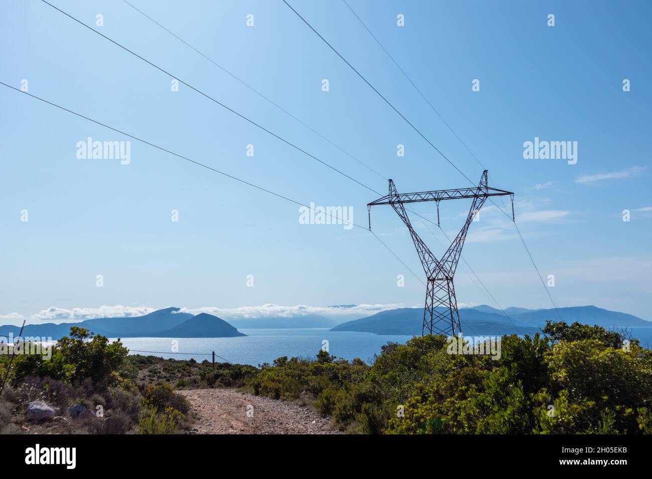 Panoramic landscape of Lefkada island coast in Greece with green woods, blue sky and electrical support line. Summer travel Stock Photo