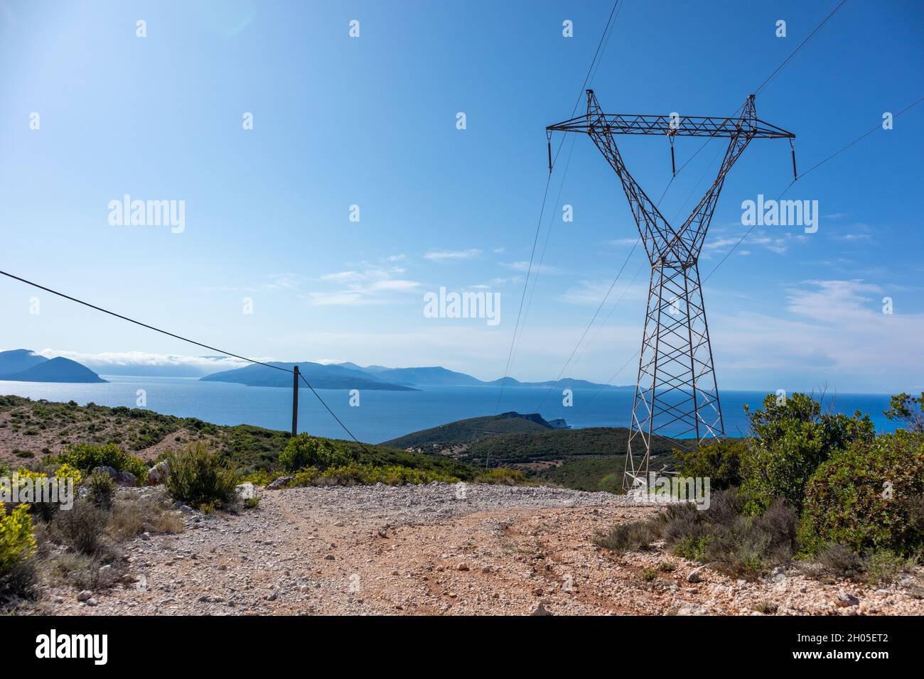 Panoramic landscape of Lefkada island hills from dirt road. Greece with green woods, blue sky and electrical support line. Summer travel Stock Photo