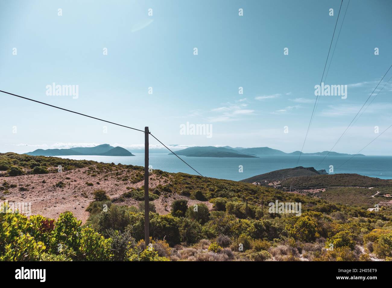 Panoramic landscape of Lefkada island coast in Greece with green woods, blue sky and electrical support line. Summer travel colors Stock Photo