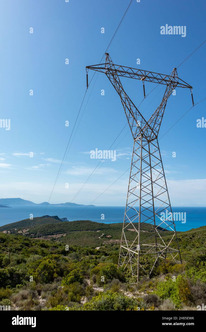 Green landscape of Lefkada island coast in Greece with green woods, blue sky and electrical support line. Vertical Stock Photo
