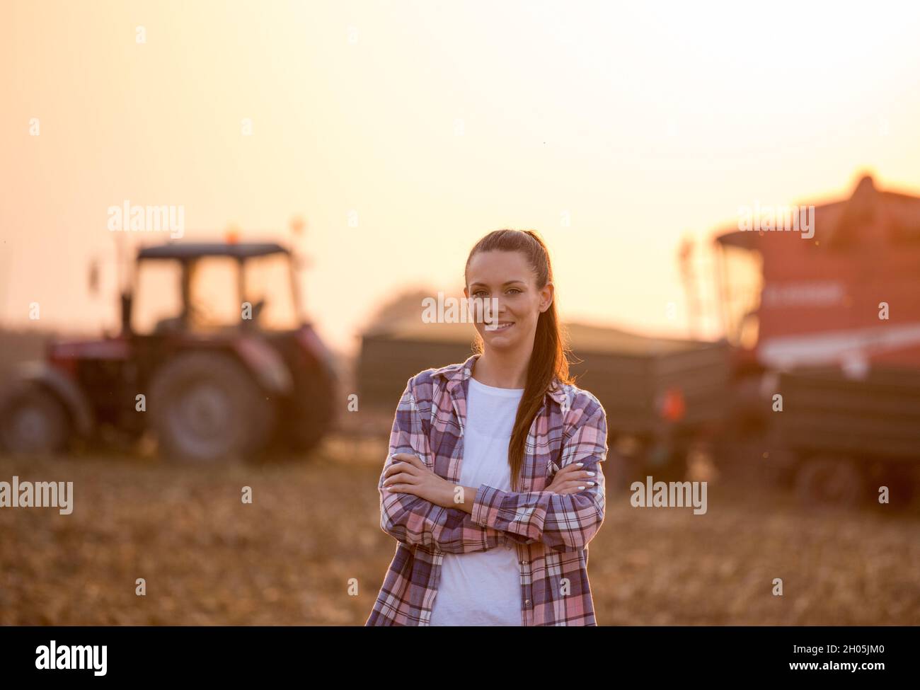 Satisfied young farmer woman standing with crossed arms in front of ...