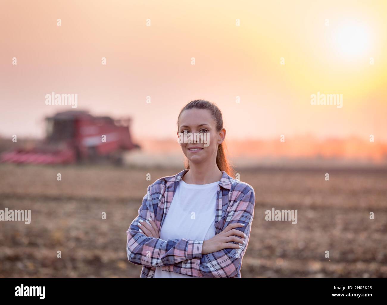Satisfied young farmer woman standing with crossed arms in front of ...