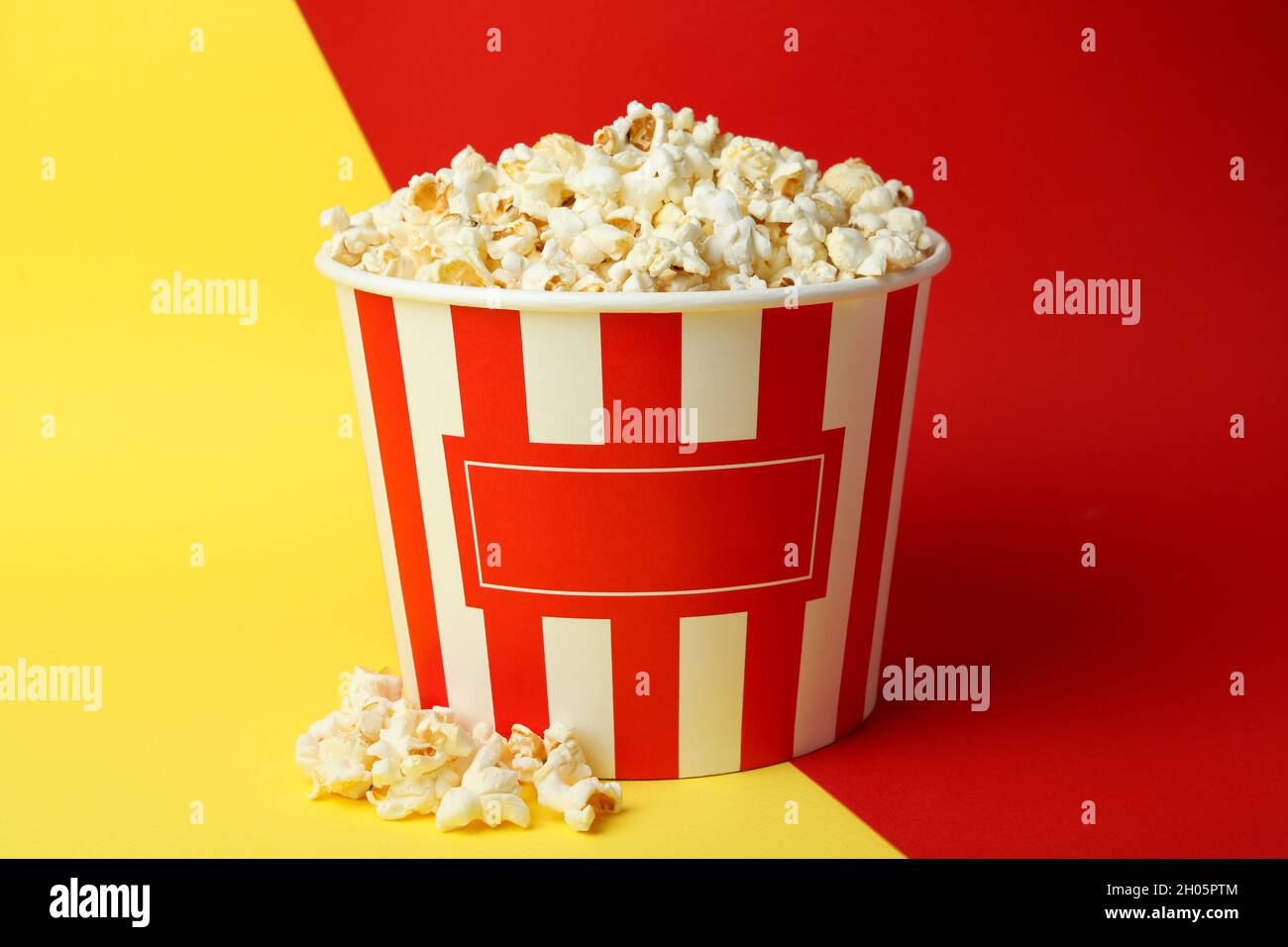 Striped paper cup with popcorn on two tone background. Stock Photo