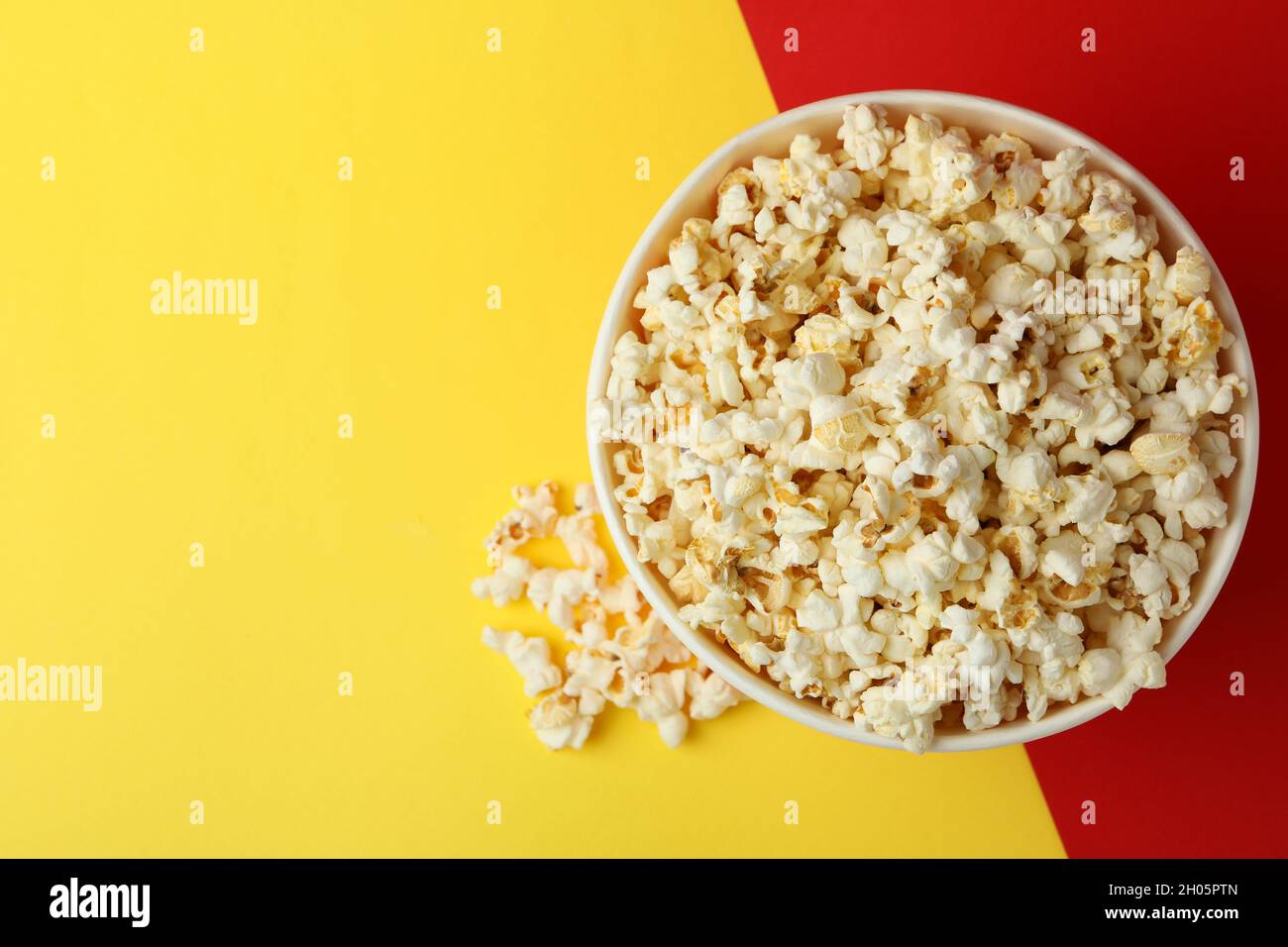 Striped paper cup with popcorn on two tone background. Stock Photo