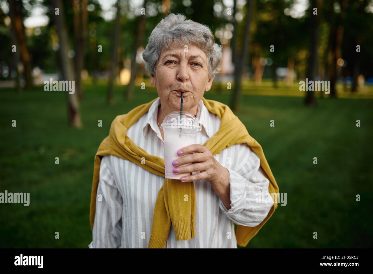 Granny drinks milk coctail, back to childhood Stock Photo Alamy