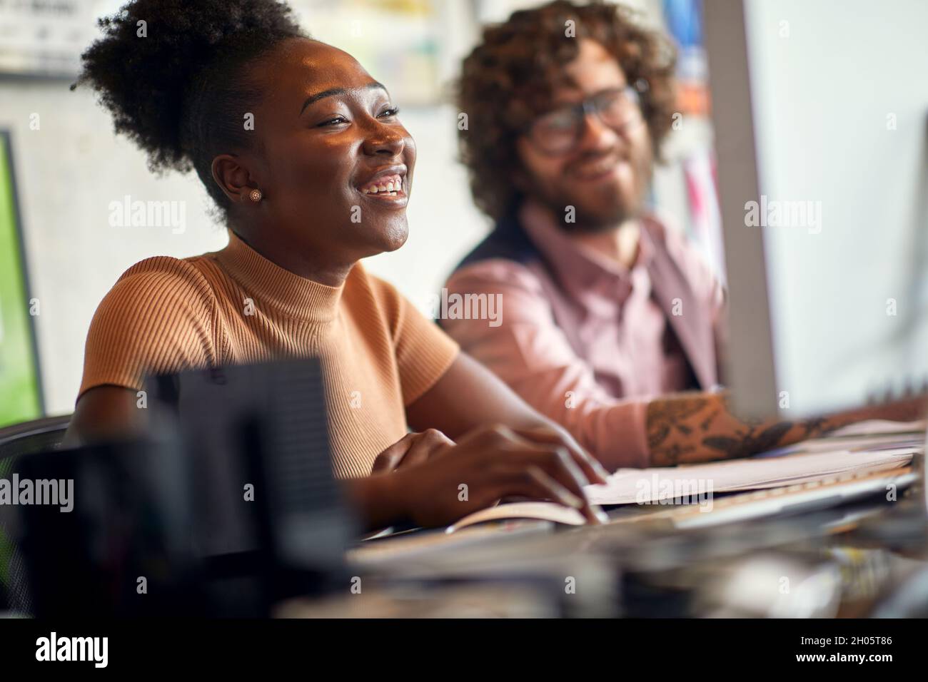 Young colleagues are in a good mood while working in a cheerful atmosphere at office together Stock Photo