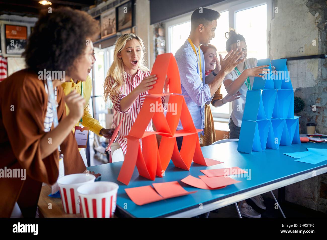 group of employees are competing in faster building paper towers at work, having fun Stock Photo