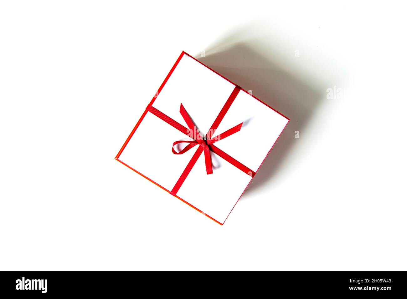 Gift white box with red ribbon and bow isolated on white. View from ...